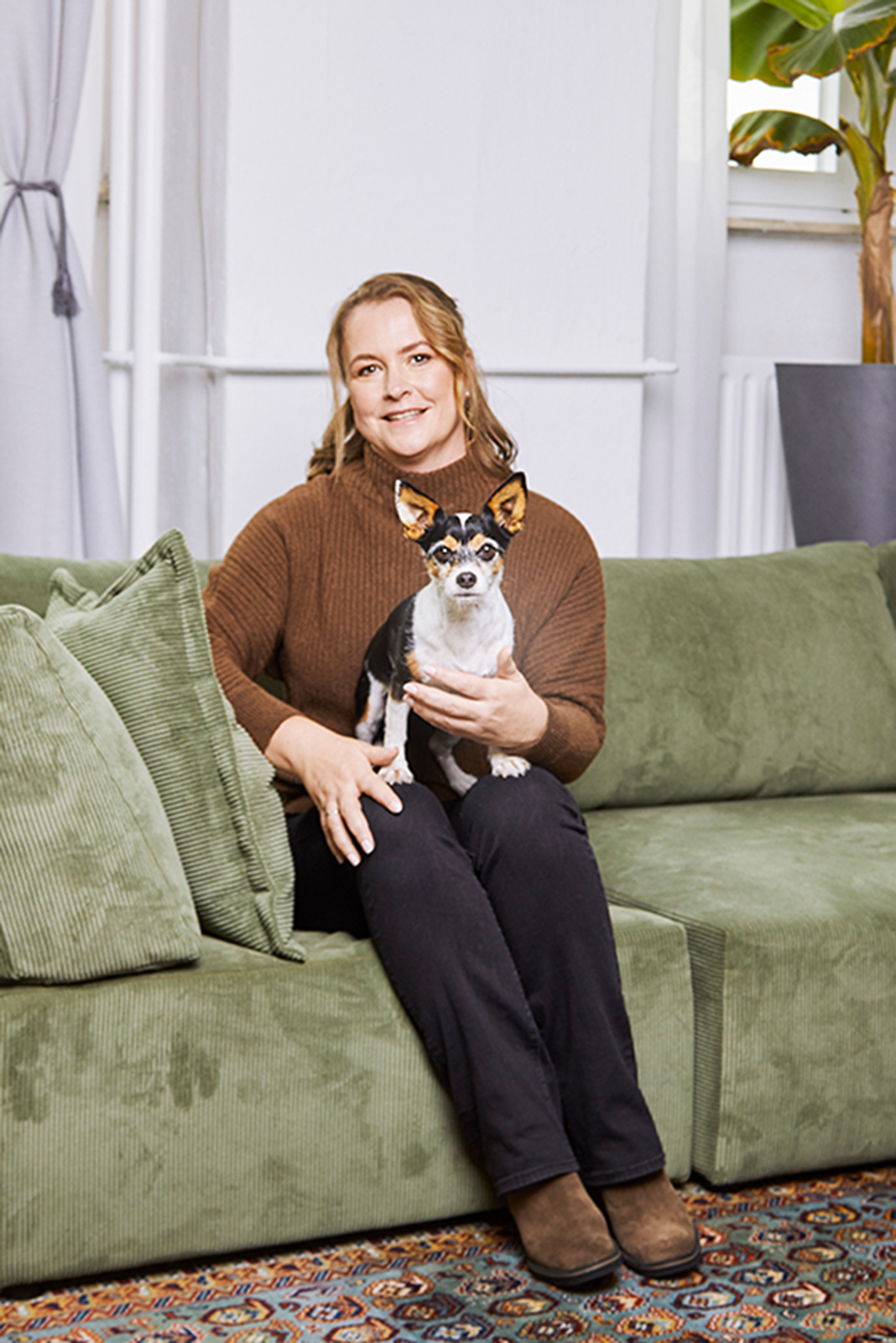 Eine Frau (Miriam) sitzt auf einem Sofa mit einem Hund (Bonnie).