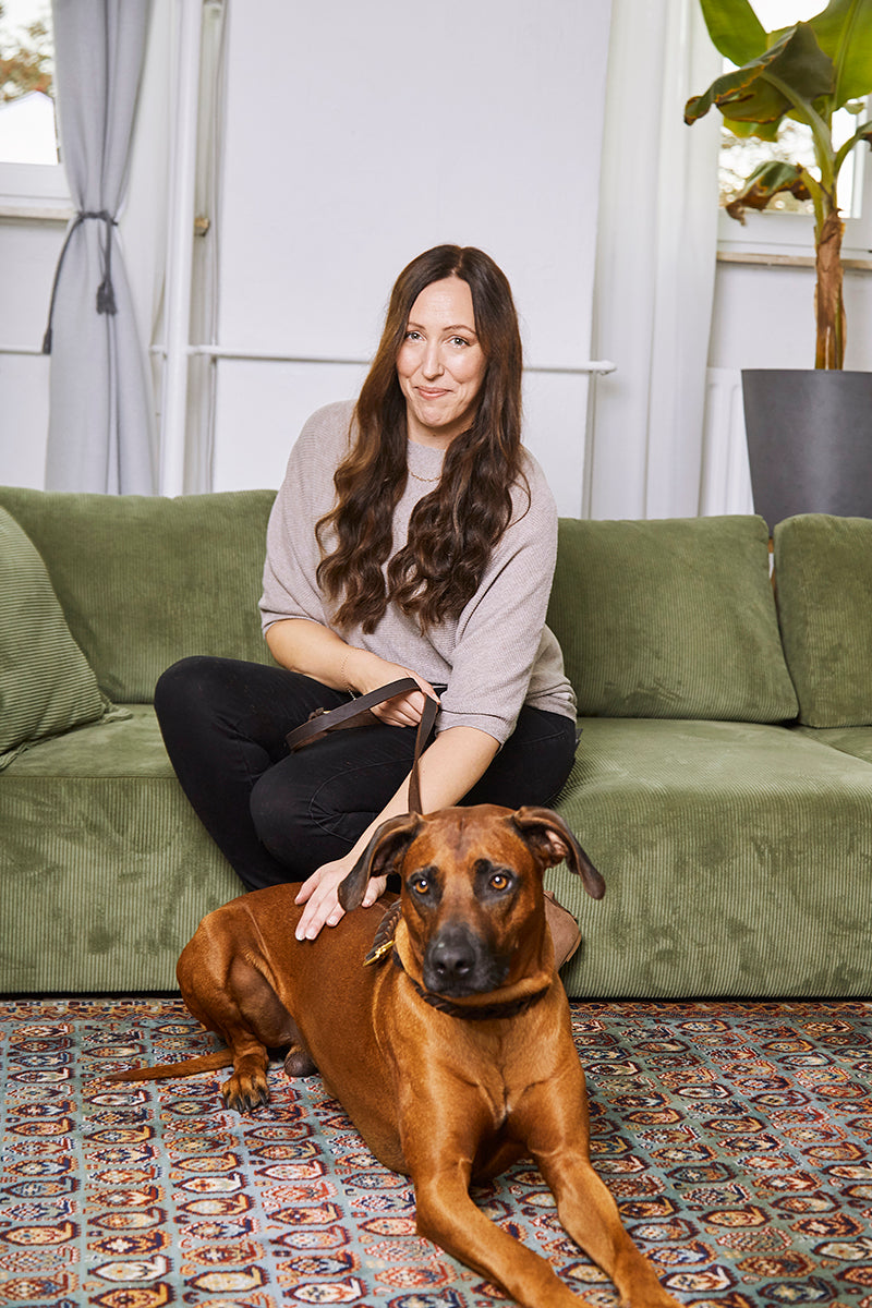Eine Frau (Ramona) sitzt auf einem Sofa mit einem Hund (Buma).